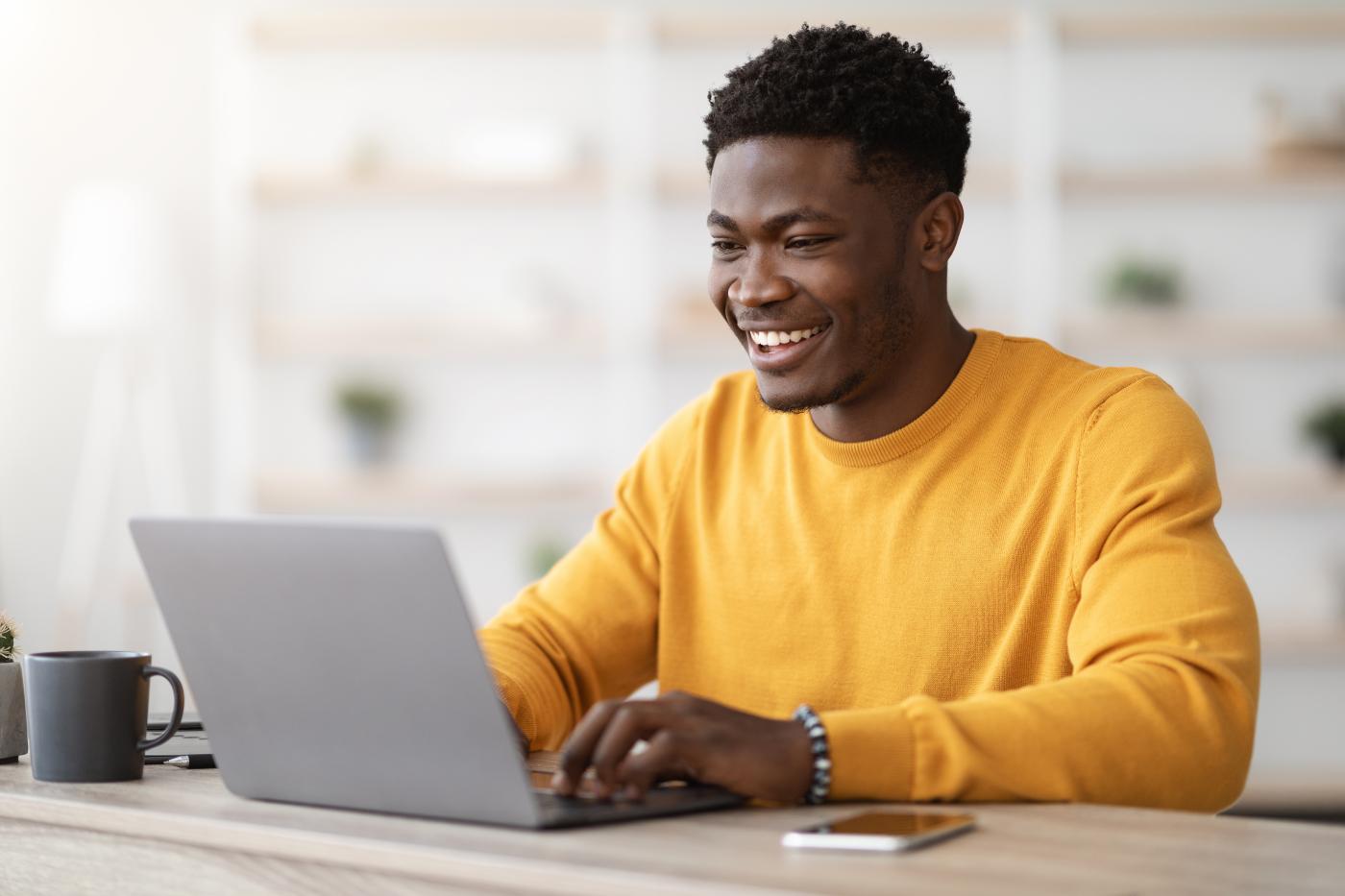 A smiling man working at his laptop.