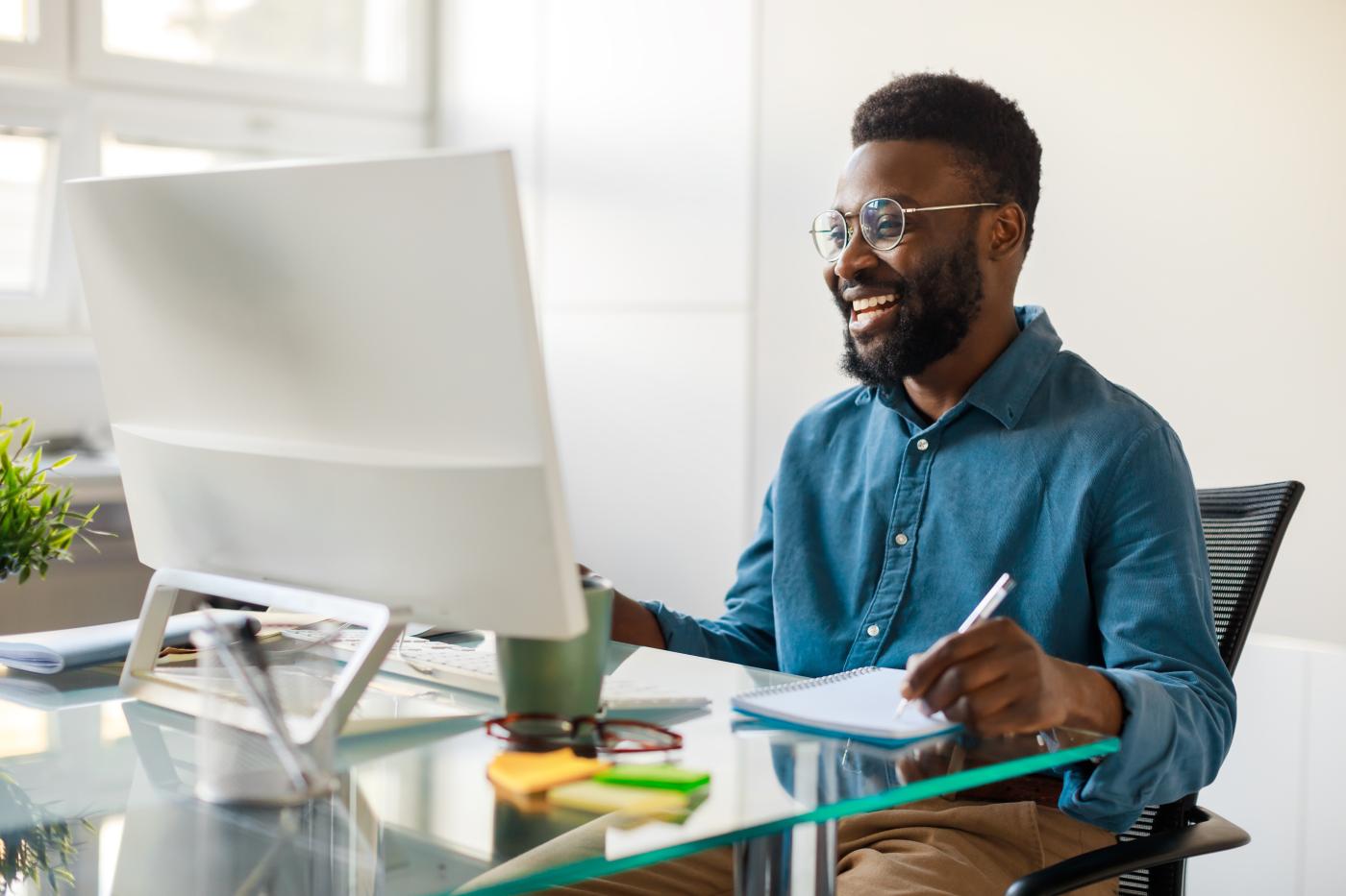 A smiling man working at his office computer.
